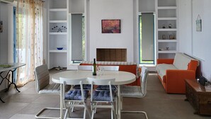 A modern living room with a round table, chairs, a sofa, and built-in shelving. - Villa Rahes,sea view,3 bedrooms,wifi,5min from the village,low prices (skopelos)