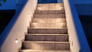 A staircase with stone steps leading to a blue door, illuminated by wall-mounted lights. - Villa Rahes,sea view,3 bedrooms,wifi,5min from the village,low prices (skopelos)