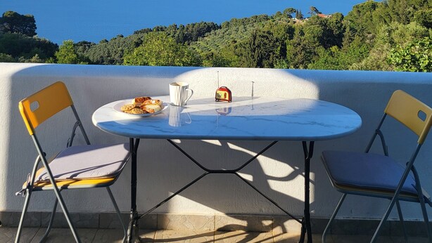 A terrace with a round table and two chairs, overlooking a scenic view of the sea and greenery. - Villa Rahes,sea view,3 bedrooms,wifi,5min from the village,low prices (skopelos)