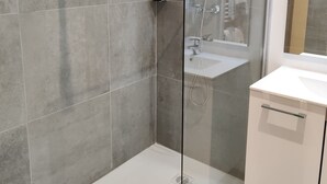 A modern bathroom with a glass-enclosed shower, a white sink, and a mirror above the sink. - Hôtel de la Tour (La Tour-du-Pin)