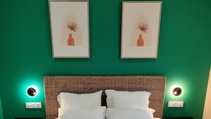 A neatly made bed with white linens and two folded towels on the bed. There are two nightstands with wall-mounted lamps and a wicker headboard. - Hôtel de la Tour (La Tour-du-Pin)