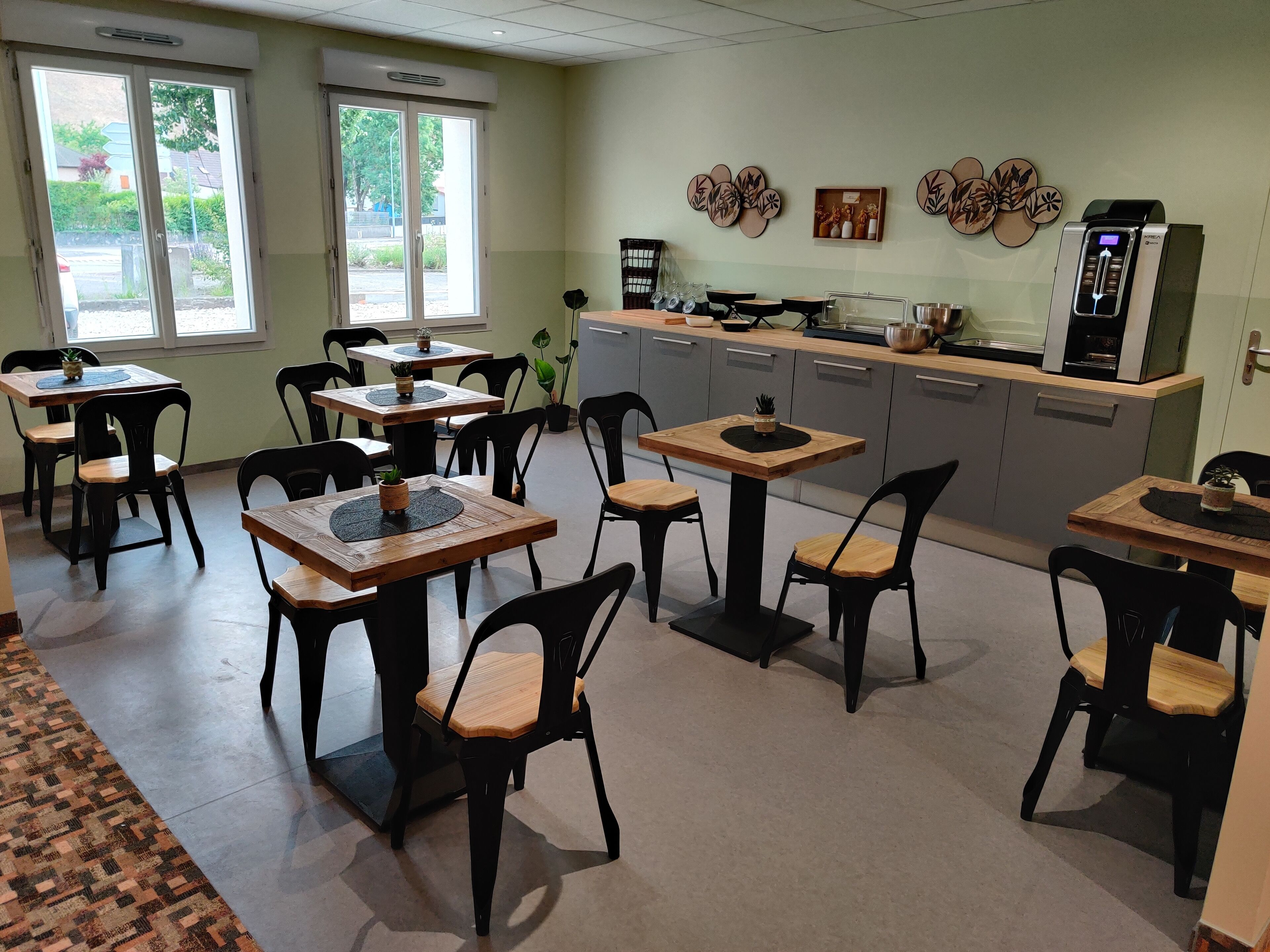 Comedor con varias mesas y sillas, zona de cocina con electrodomésticos y decoración en la pared.