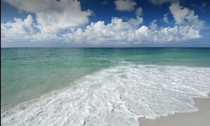 A beach with clear turquoise water and white foam waves.