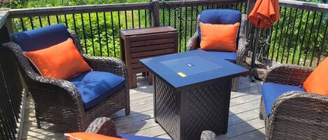 A deck with wicker furniture, a table, and a view of a body of water.