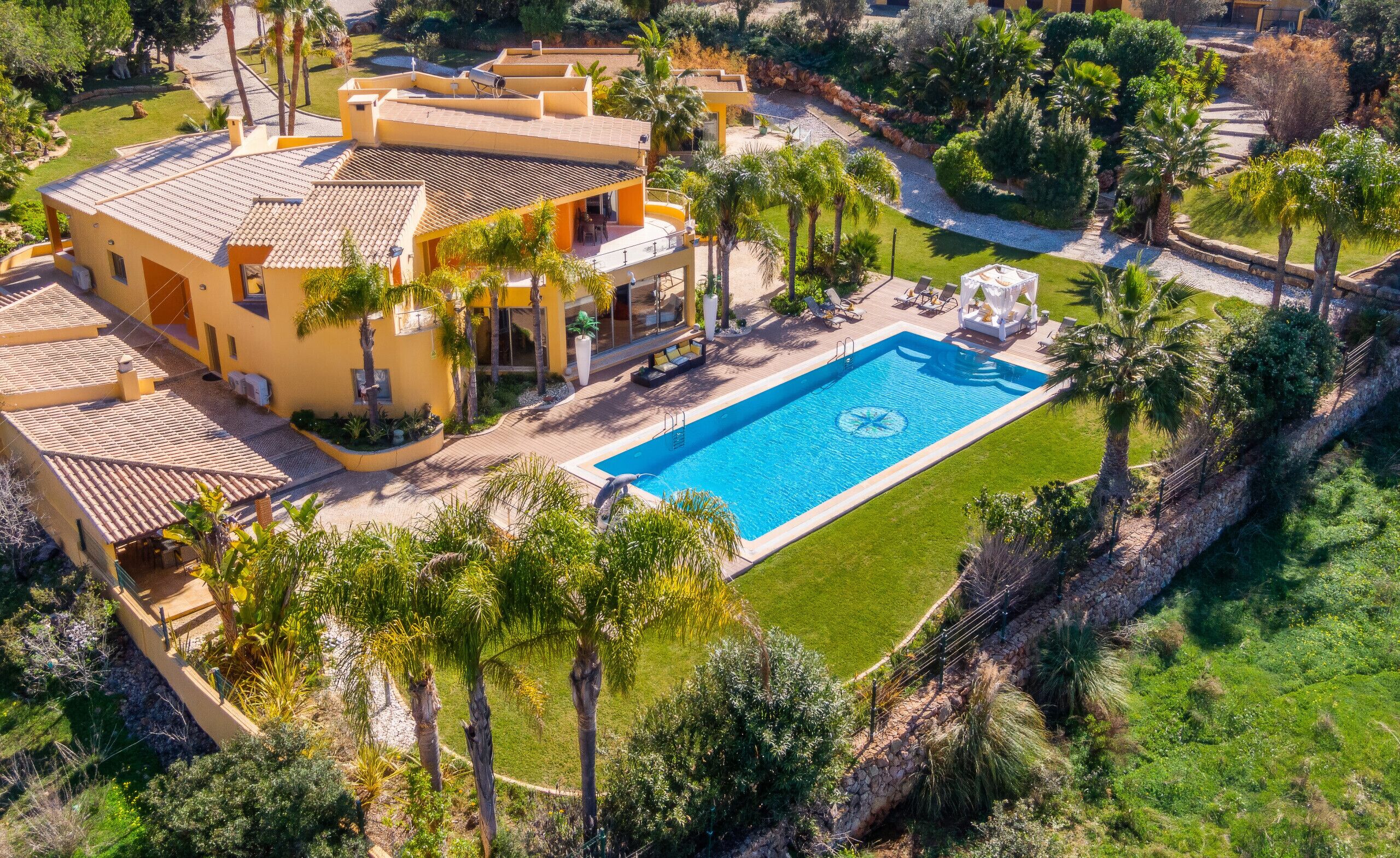 A large building with multiple balconies, a swimming pool, and surrounding greenery.
