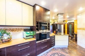 A modern kitchen with dark cabinetry, a built-in oven, and a central island with a sink.
