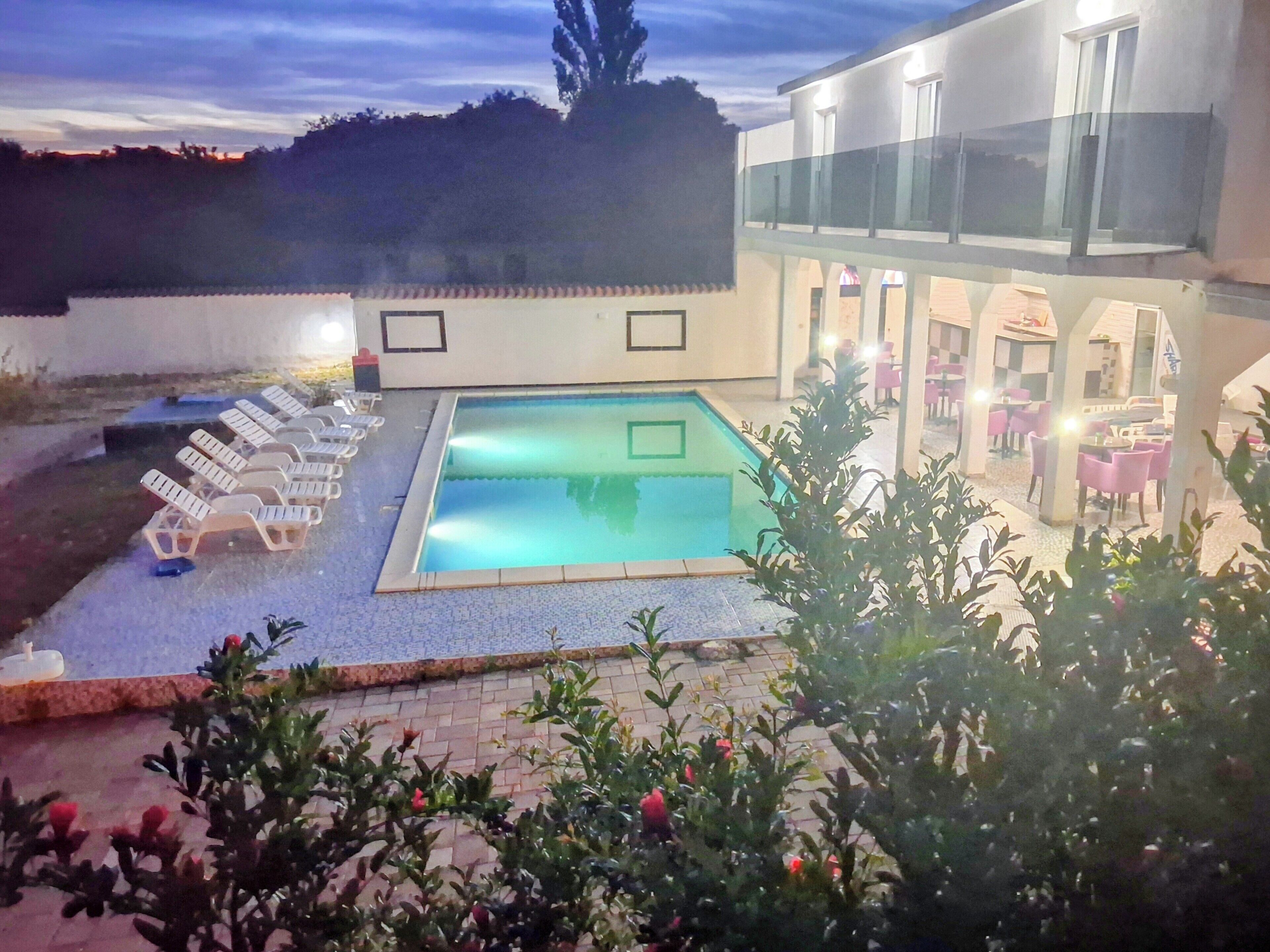 Una piscina con sillas de descanso, un patio y un edificio con fachada de vidrio.