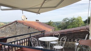 Una terraza con mesa y sillas, una planta en maceta y vistas del paisaje circundante.