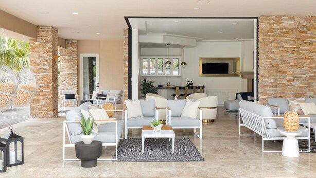 Un vaste espace de vie au design moderne, comprenant un mélange de canapés et de fauteuils, une table basse et un grand tapis.