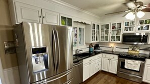 Una cocina moderna con electrodomésticos de acero inoxidable, armarios blancos y piso de madera.