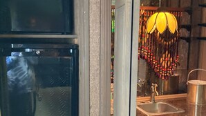 Una cocina con armarios de madera, un lavamanos de acero inoxidable y un refrigerador negro.
