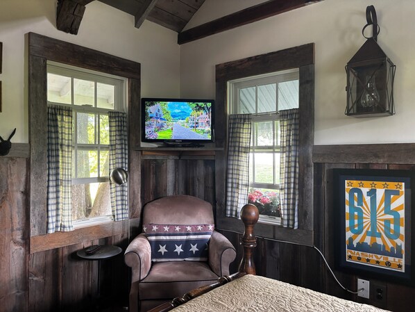 A cozy room with a wooden chair, a television, and a framed poster.