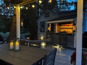 A wooden deck with outdoor seating, a small bar area, and string lights.
