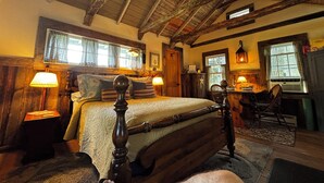 Une chambre à coucher rustique avec un lit à baldaquin en bois, un bureau avec une chaise et un lustre.