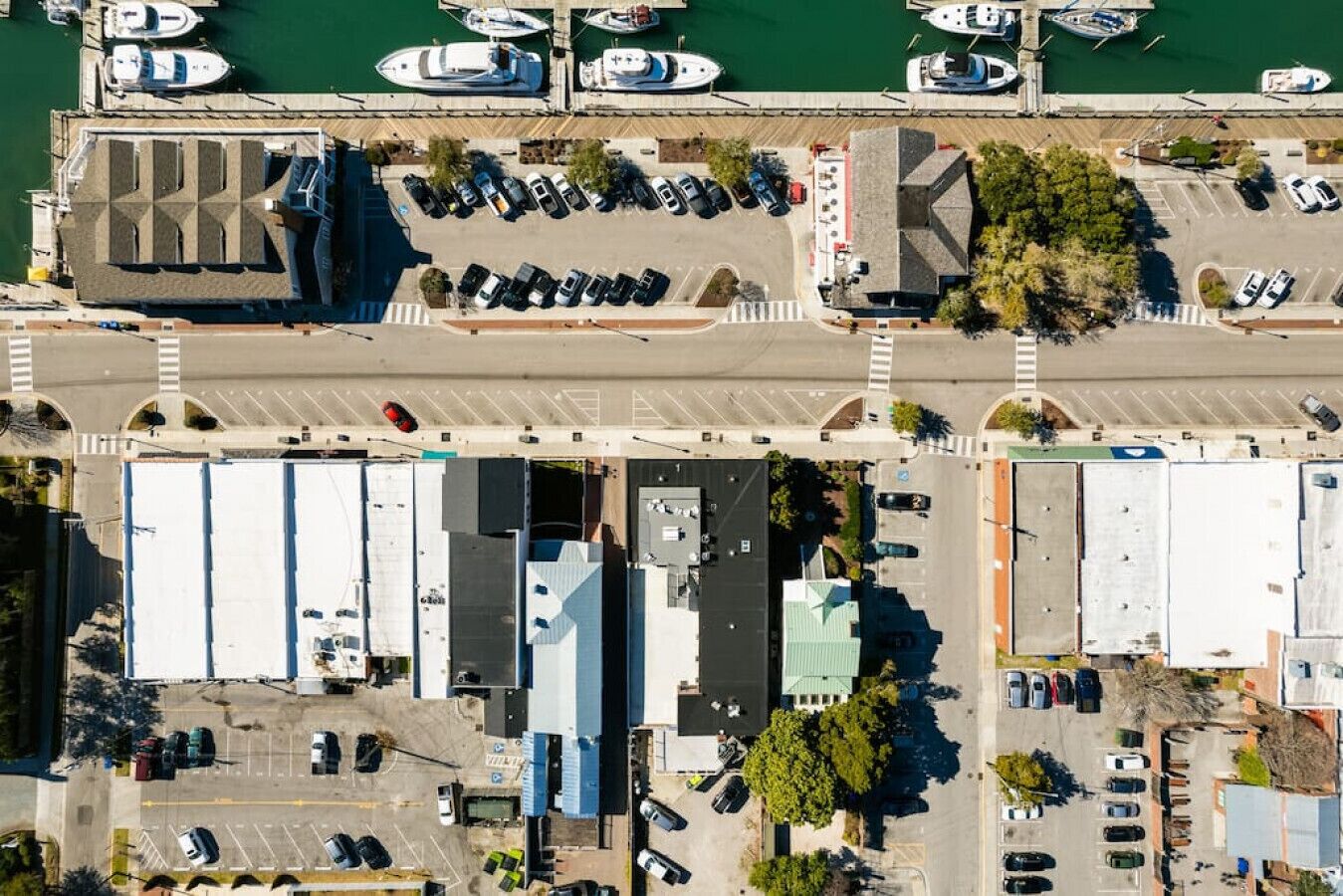 Ein Luftbild eines Yachthafens mit angestaubten Booten, einem Parkplatz und Gebäuden mit flachen Dächern.