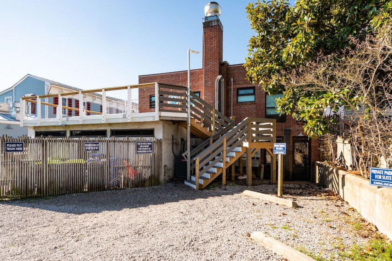 Un área de estacionamiento amparada con una escalera que lleva a un edificio con una chimenea de ladrillo.