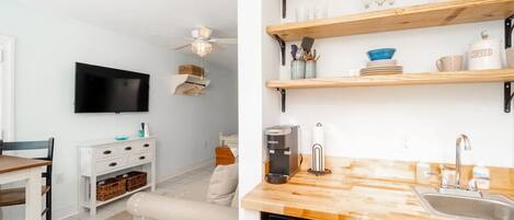 A modern kitchen with wooden shelves, a coffee maker, and a sink.