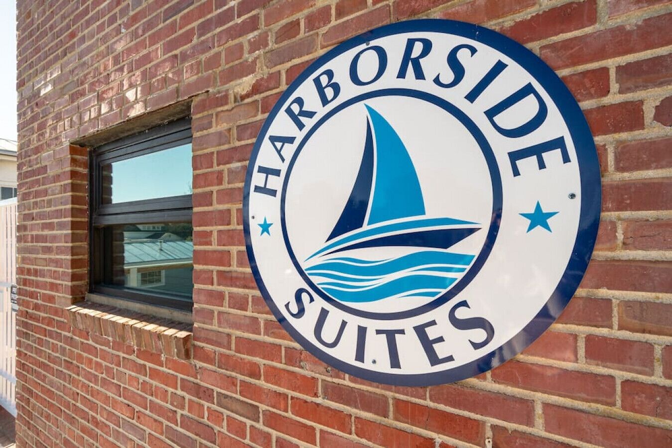 A circular sign with a sailboat and waves, indicating a hotel named "Harborside Suites."