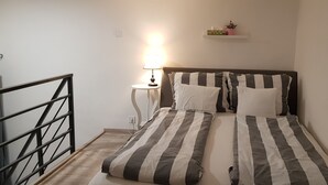 A bedroom with a bed, a nightstand, a lamp, and a shelf with decorative items.