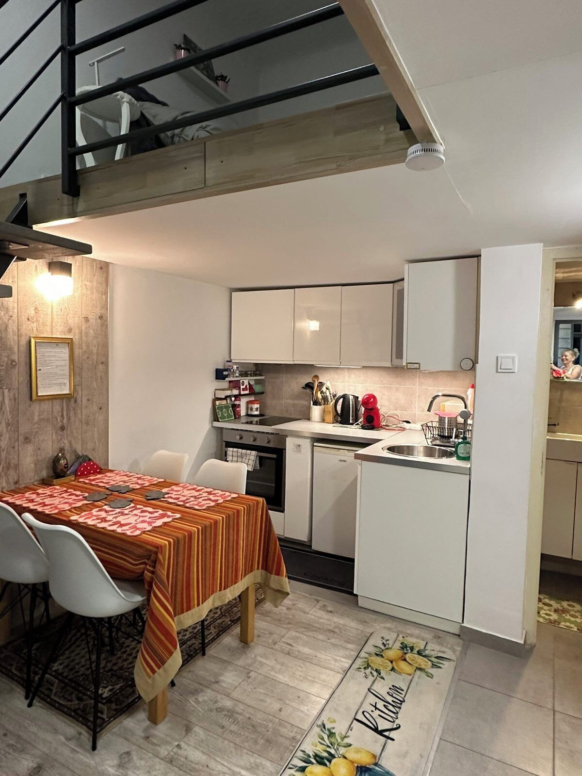 A compact kitchen with white cabinets, a dining table with a striped tablecloth, and a kitchen island.