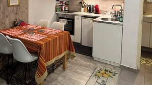 A compact kitchen with white cabinets, a dining table with a striped tablecloth, and a kitchen island.