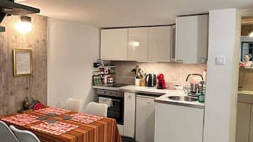 A compact kitchen with white cabinets, a dining table with a striped tablecloth, and a kitchen island.