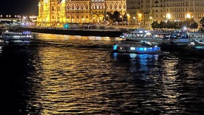 A large, illuminated building with a prominent dome and spires, situated by a body of water with reflections.