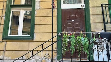 A building with a brown door, green-framed windows, and a metal staircase.