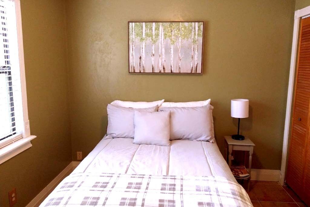 Un dormitorio con una cama, una mesita de noche con una lámpara y un cuadro en la pared.