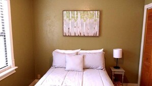 Ein Schlafzimmer mit einem Bett, einem Nachttisch mit Lampe und einem Bild an der Wand.