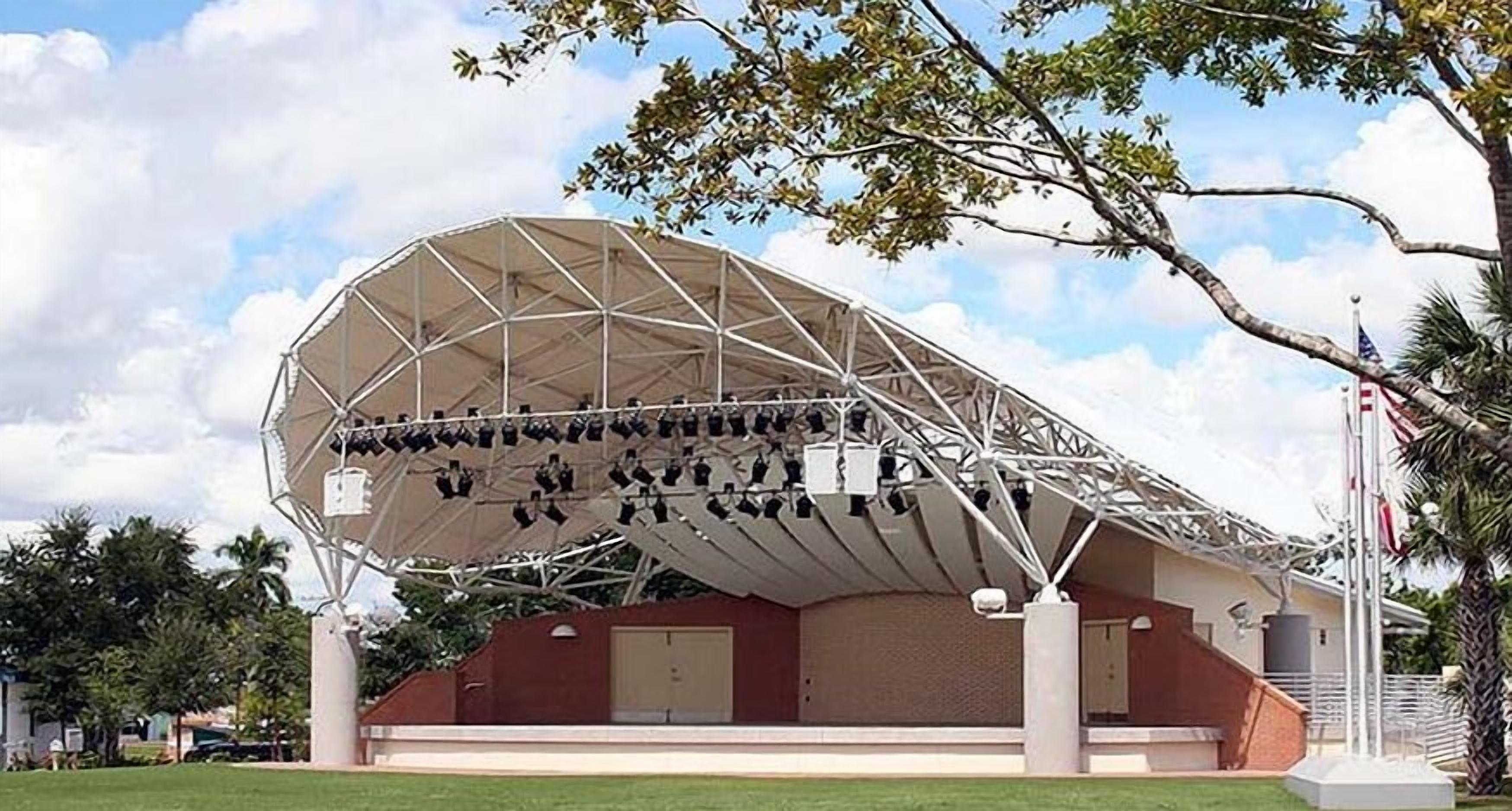 Una gran estructura en forma de cúpula geodésica blanca con múltiples antenas parabólicas en su superficie, sobre un fondo de cielo despejado y palmeras.