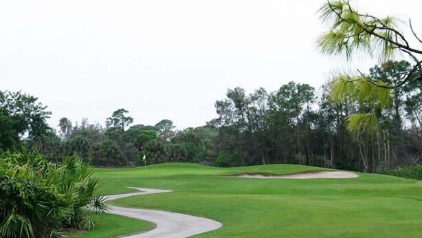 Ein Golfplatz mit einem gewundenen Weg, umgeben von dichtem Grün und Bäumen.