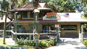 A building with a sign reading "Song of the River Golf & Exploration Co." and another sign for "Alligator Isle."