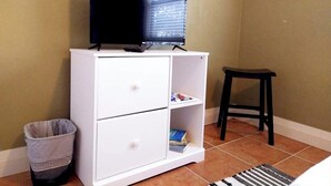 Ein Zimmer mit einem weißen Schrank, einem schwarzen Hocker und einem Mülleimer.