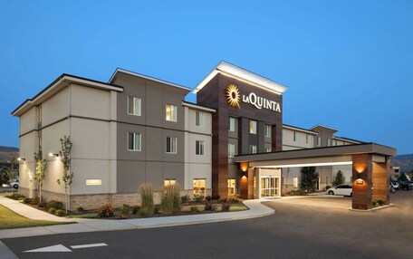 A La Quinta hotel with a modern design, featuring a large entrance, multiple windows, and a well-lit facade.