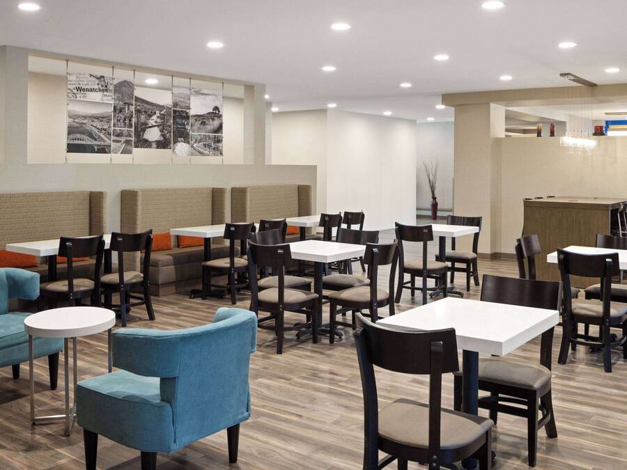 Een modern restaurant met zitjes en tafels, een muur met een stadsgezichtsmural en een bedieningsgedeelte.