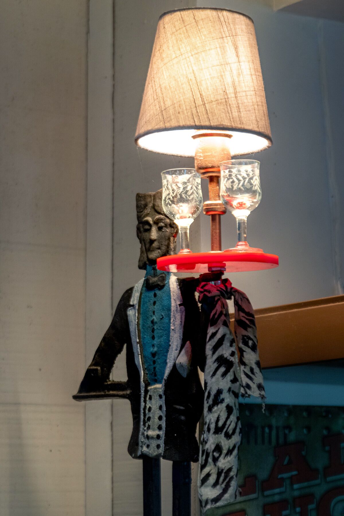 Un mannequin sur lequel sont posés une lampe et deux verres.