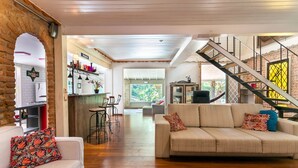 A spacious living area with a sofa, a coffee table, and a staircase. - Boutique chalet amidst the Atlantic rainforest. (PETRÓPOLIS)