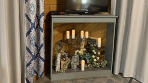 Una habitación con una televisión sobre un mueble bajo, un candelabro con velas y una alfombra estampada.