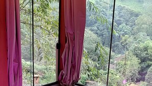 A spa room with a large bathtub, wooden ceiling, and a view of a lush landscape through large windows. - Pousada Caminho do Escorrega (Itatiaia)