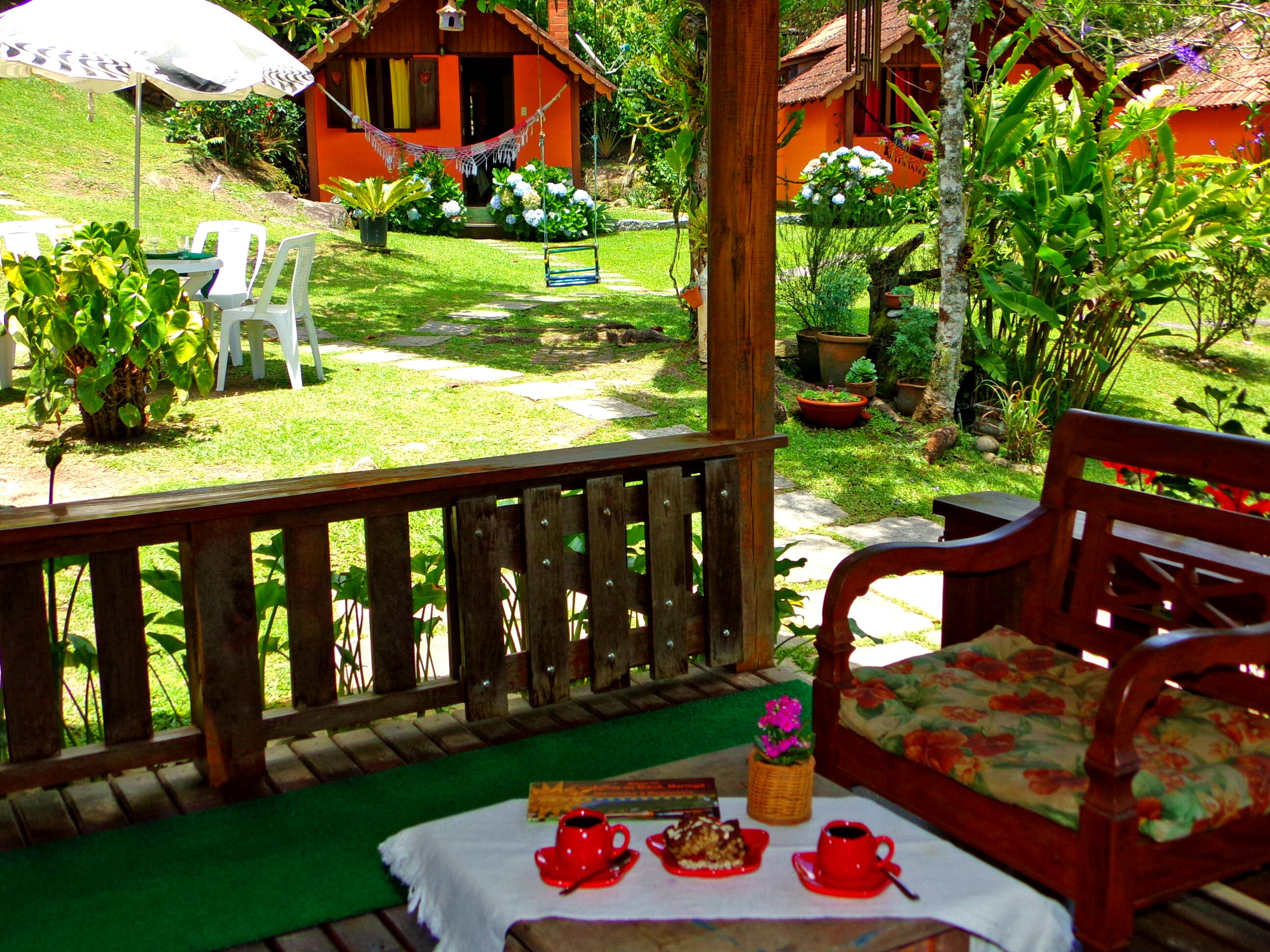 A wooden deck with a table set for a meal, surrounded by lush greenery and a small garden.