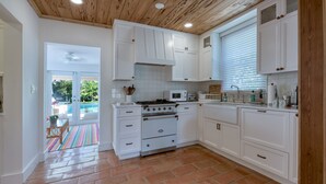 Une cuisine avec des meubles blancs, une cuisinière et un four à micro-ondes.