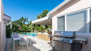 Une terrasse extérieure équipée d’un barbecue, d’une table à manger, de chaises et d’une piscine.