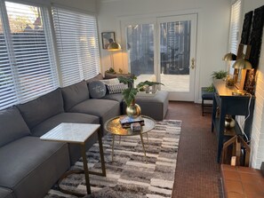 A modern living room with a grey sectional sofa, a glass coffee table, and a patterned rug.