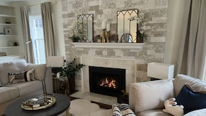 A living room with a fireplace, a sofa, a coffee table, and a side table with a plant. - Remodeled Colonial Retreat Close to  Shops and Dining (Wichita)
