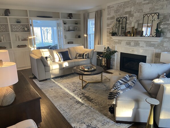 A modern living room with a fireplace, a sofa set, a coffee table, and a bookshelf.