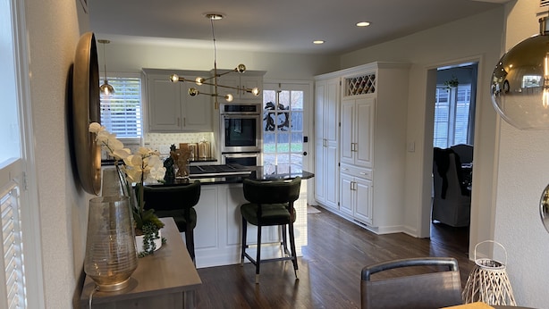 A modern kitchen with a central island, stainless steel appliances, and a dining area with a table and chairs. - Remodeled Colonial Retreat Close to  Shops and Dining (Wichita)
