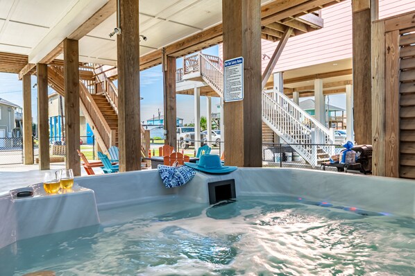 A hot tub area with wooden beams, a covered seating area, and a sign indicating safety rules.