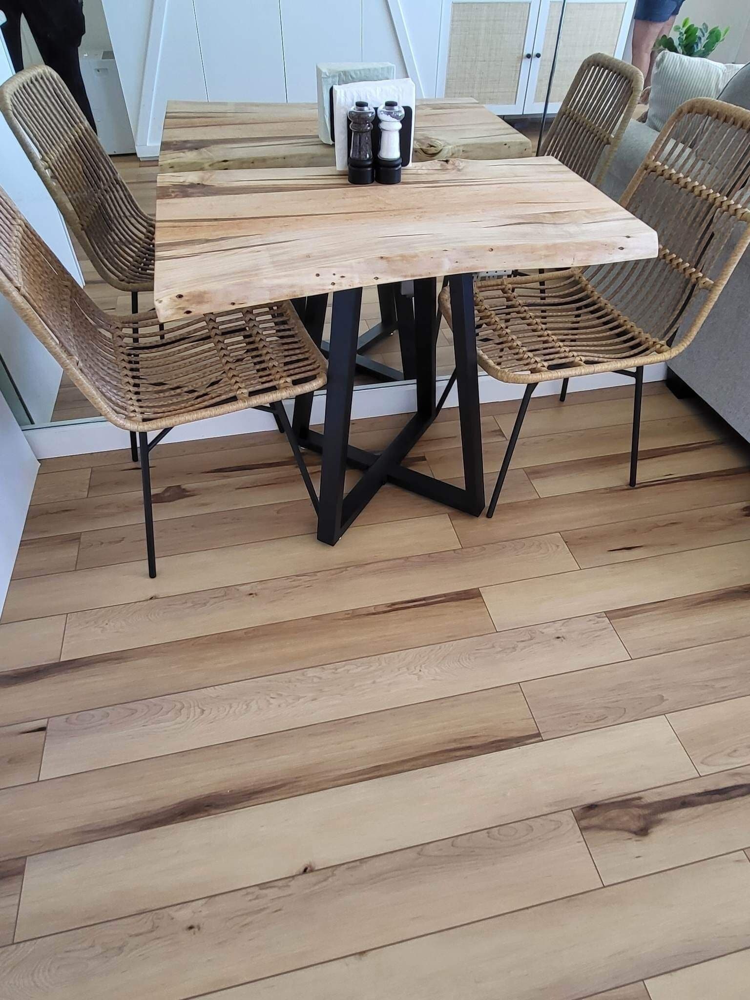 A wooden dining table with black metal legs, surrounded by woven wicker chairs.