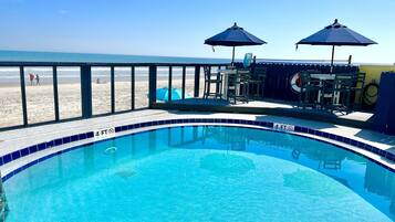 Una piscina al aire libre, sombrillas, sillones reclinables de piscina